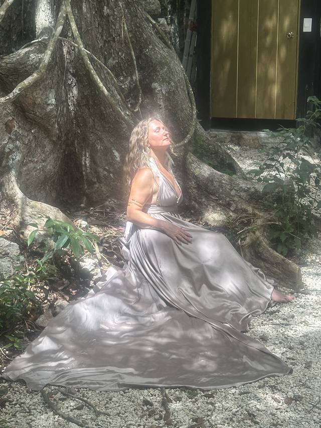 Anya seated in silver silk at the roots of a great jungle tree, sunlight crowning her hair