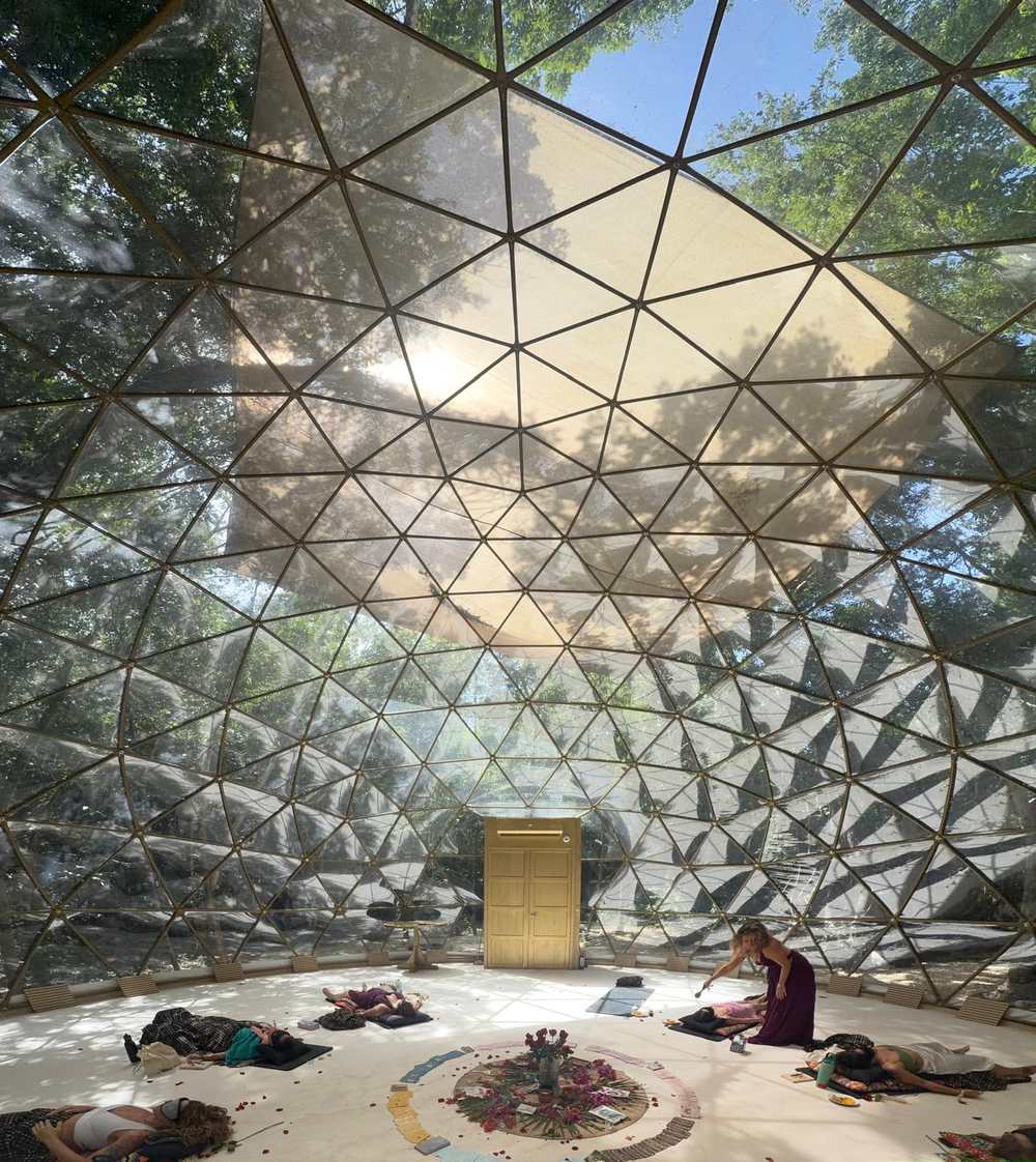 Sunlight streaming through the gold geodesic dome at Amaite Retreat Center, sisters resting in ceremony below