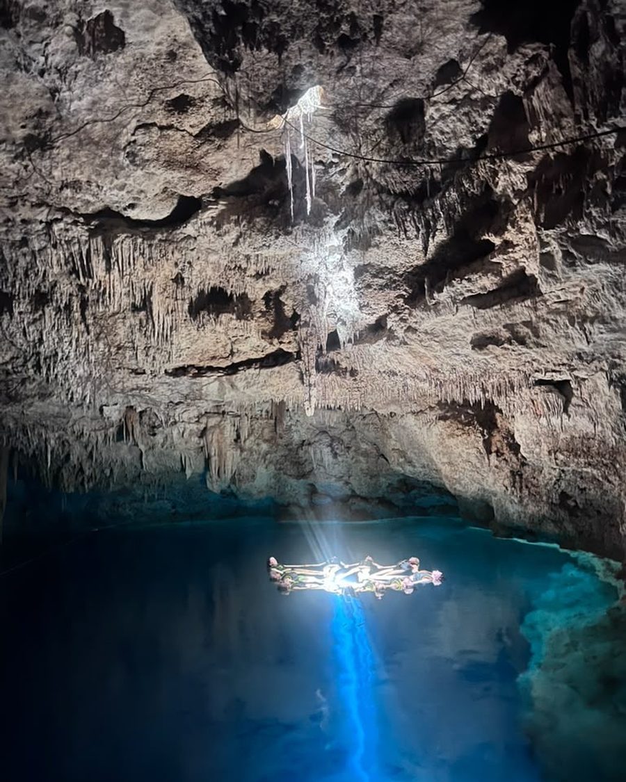 Sisters floating in a circle in the cave cenote beneath a single column of light