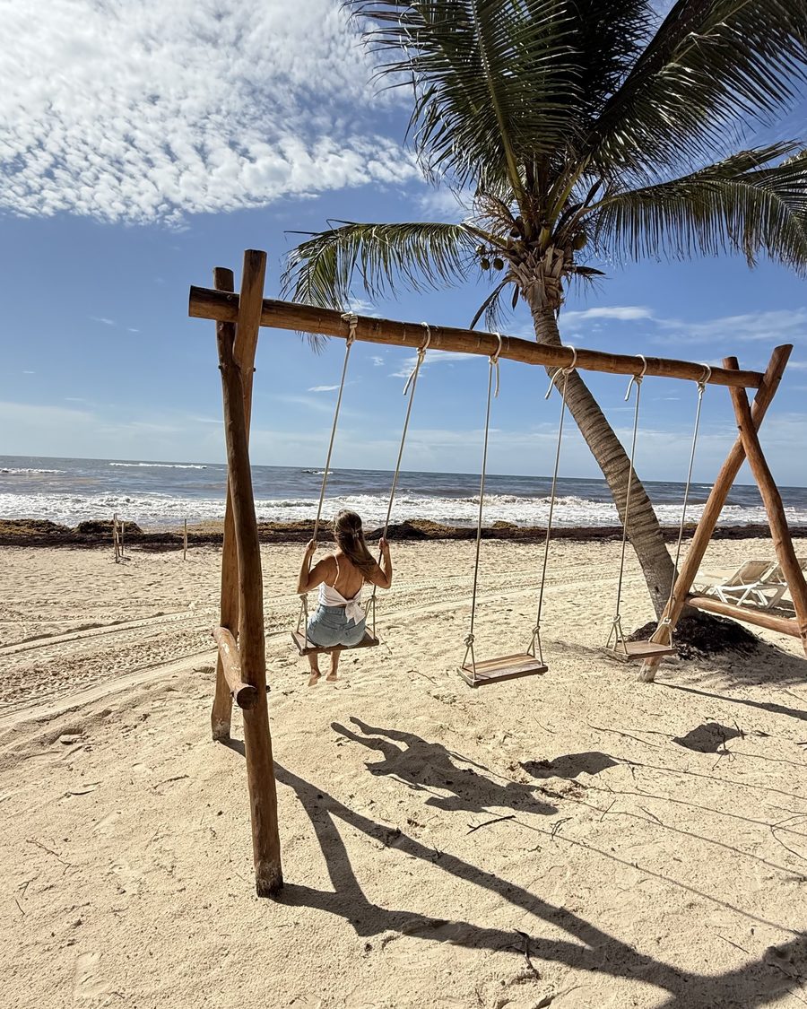 A sister on the beach swing under the palms looking out to the Caribbean