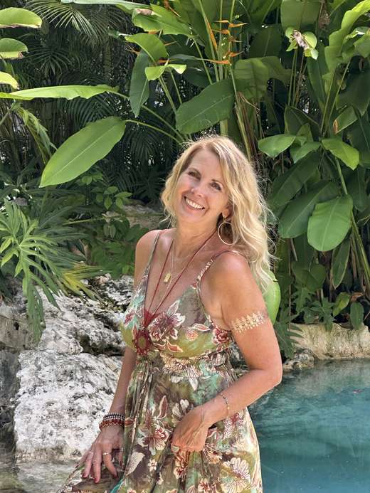 Kristi smiling among jungle palms beside the cenote
