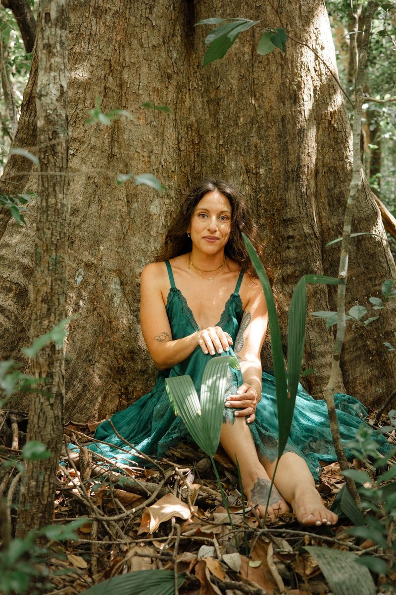 Amy in teal lace, seated at the base of a great tree