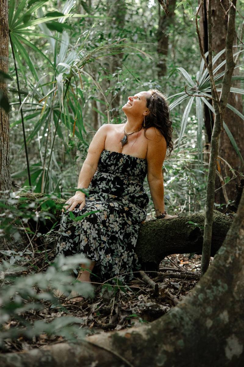 Jessica seated on a mossy log, her face turned to the light
